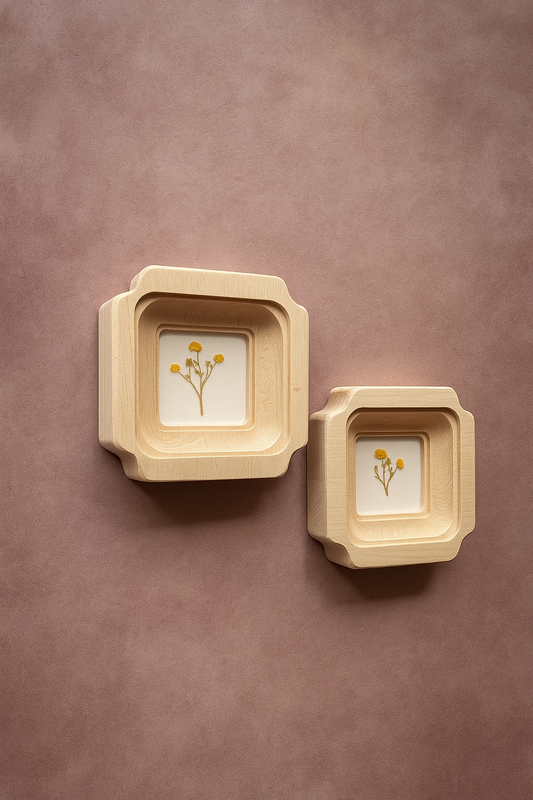 Two beige square wall frames with floral prints on a brown background