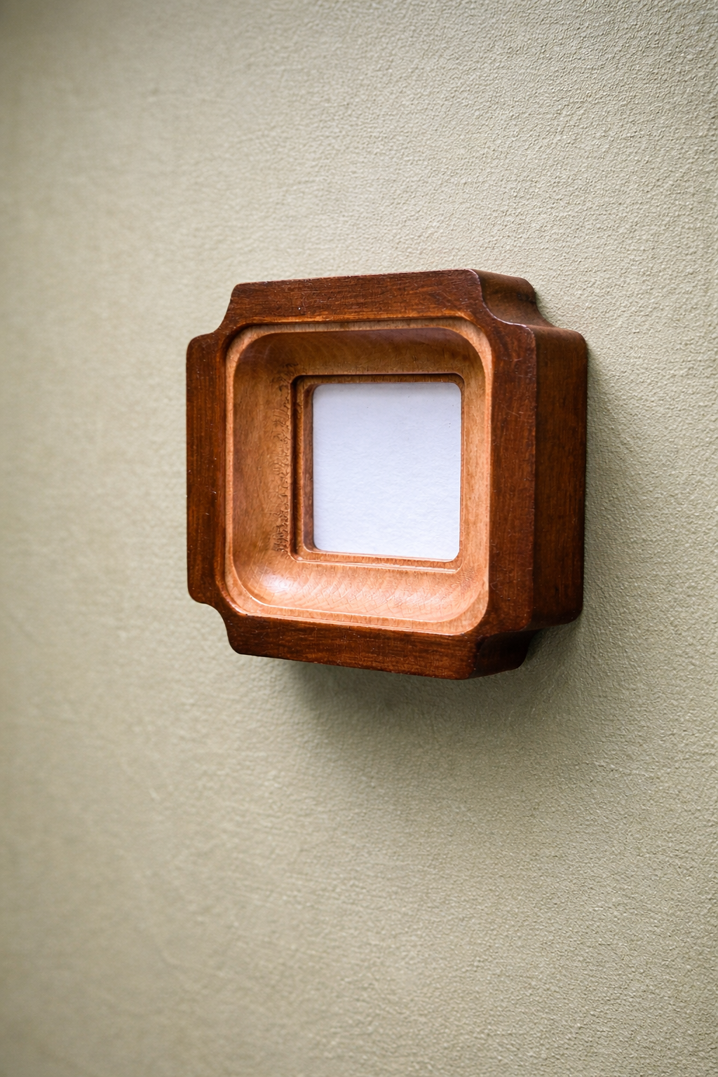 Wooden square frame on a beige wall